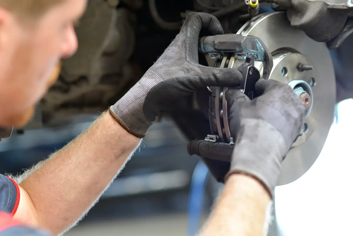 Gloved hands fitting brake pads to a rotor