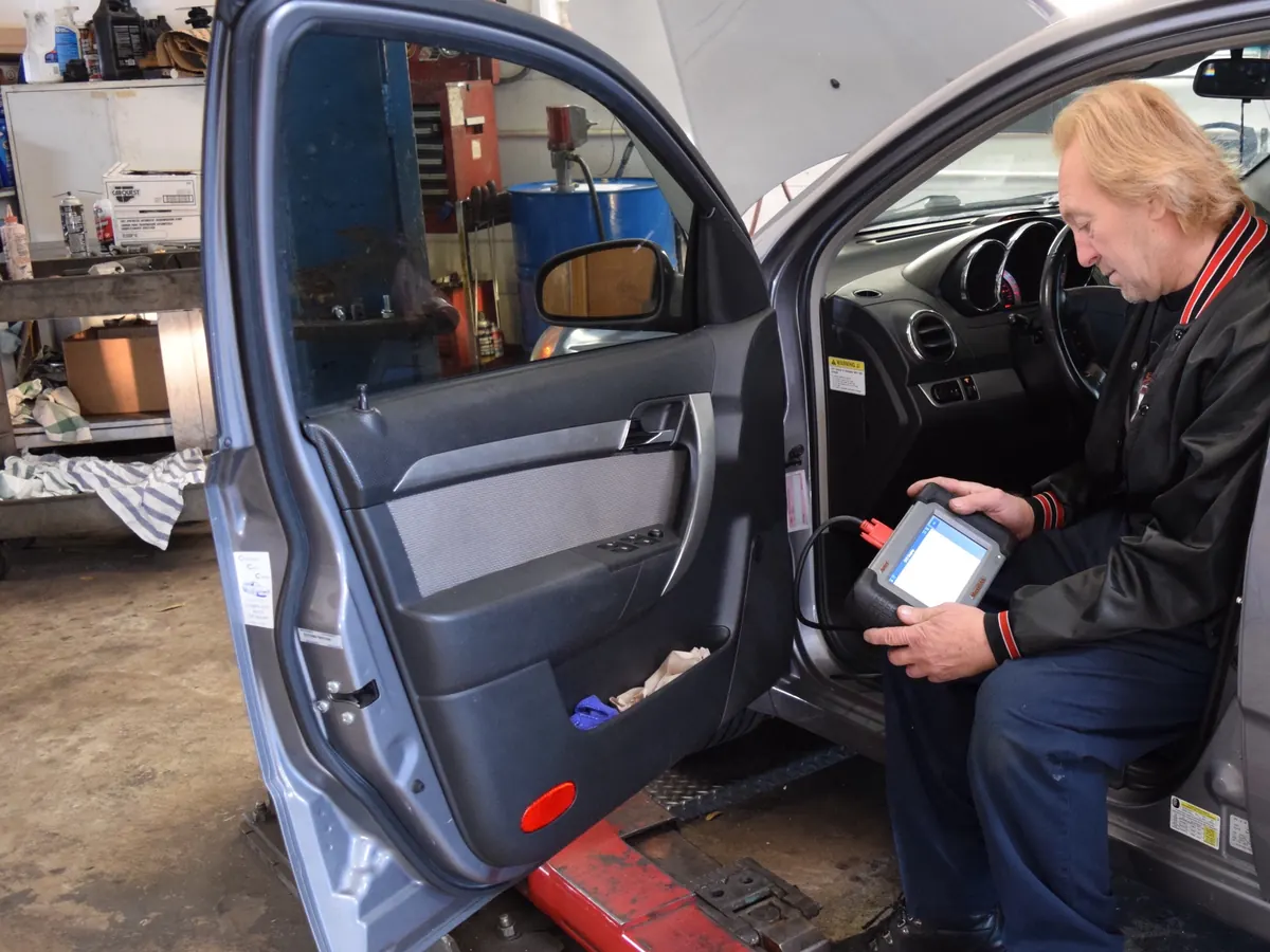 A member of the Dan's Auto team reading a diagnostic scanner from the driver's seat