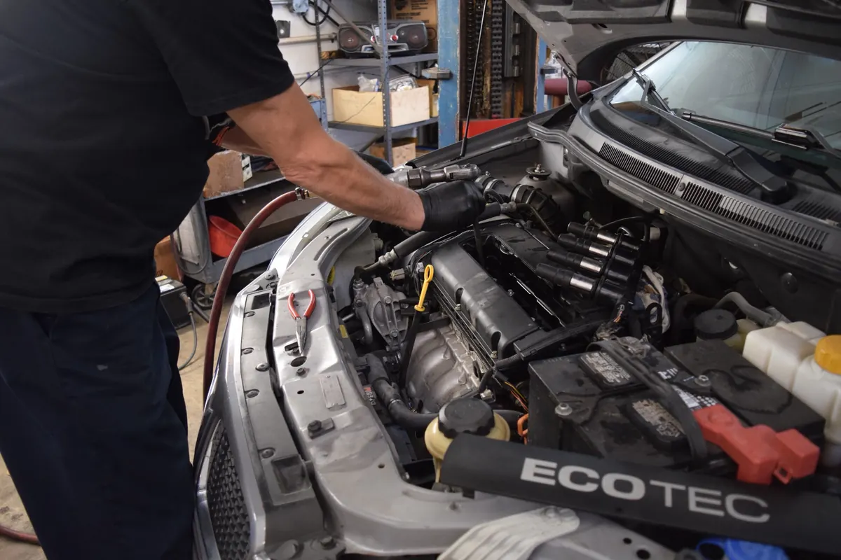 A member of the Dan's Auto team working on a car engine