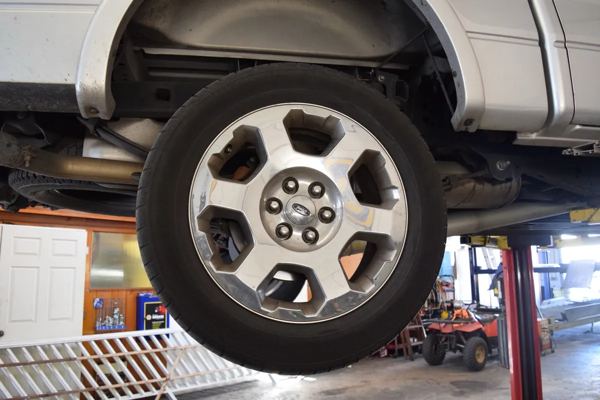 A wheel and tire on a truck raised on the lift